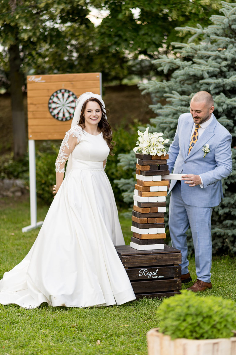 Miri jucând Jenga gigant personalizat Royal Event Games la nuntă, lângă o țintă de darts din lemn